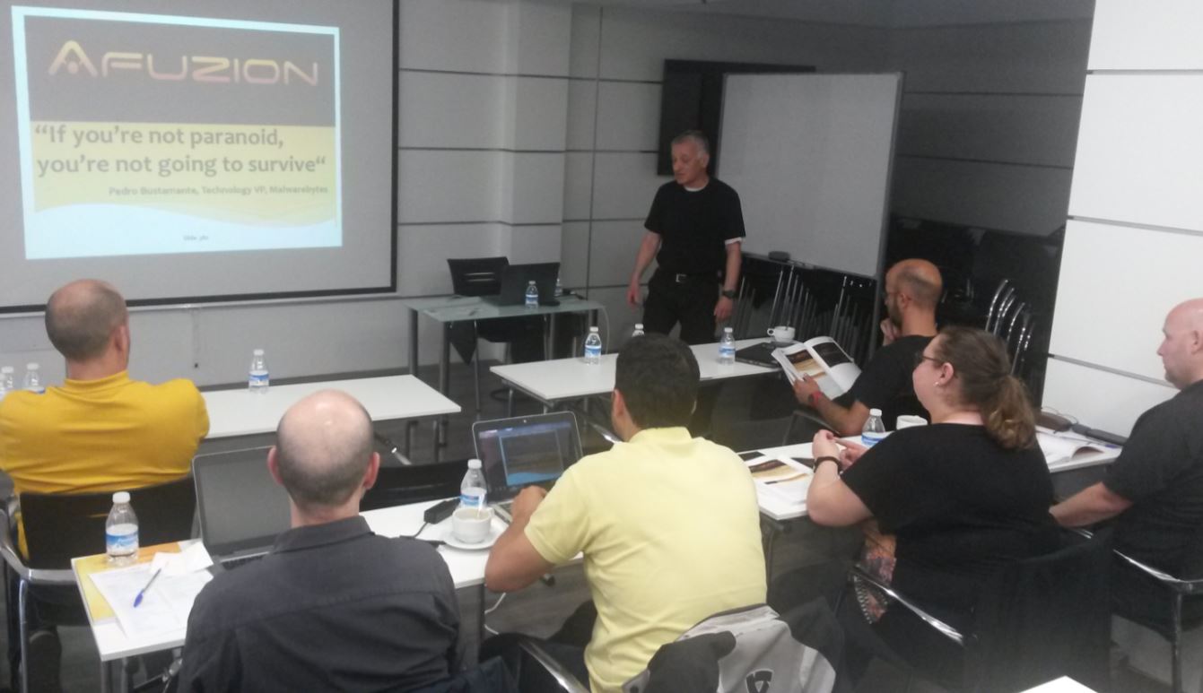 A presenter standing in front of a screen with a quote on Aviation Cyber-Security, addressing attendees in a conference room setting. | Afuzion