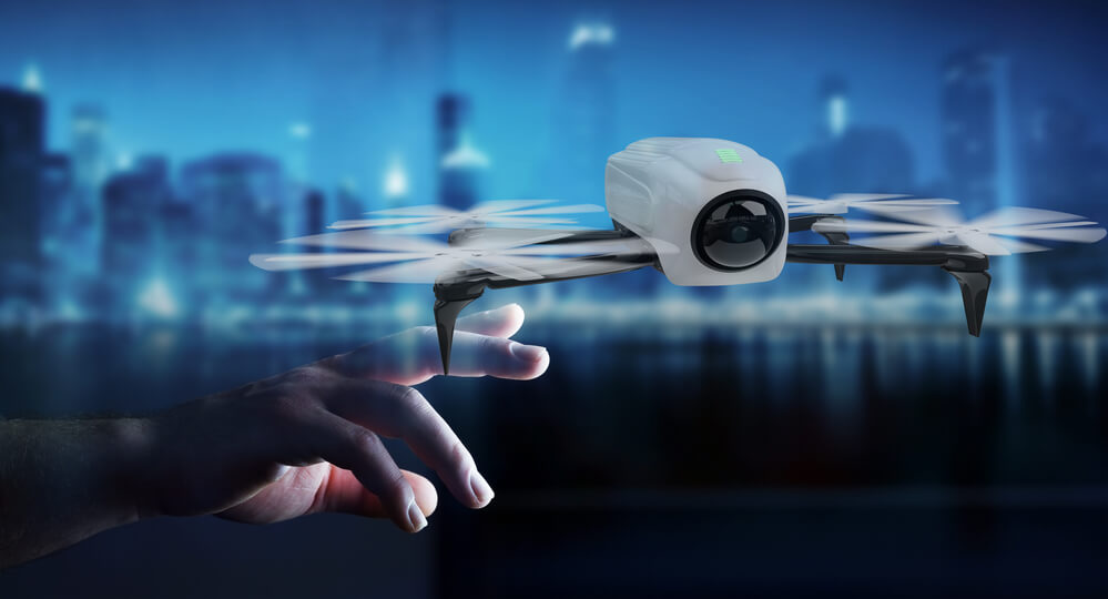 A drone with a camera, sponsored by Afuzion, hovers above a person's outstretched hand against a cityscape at twilight. | Afuzion