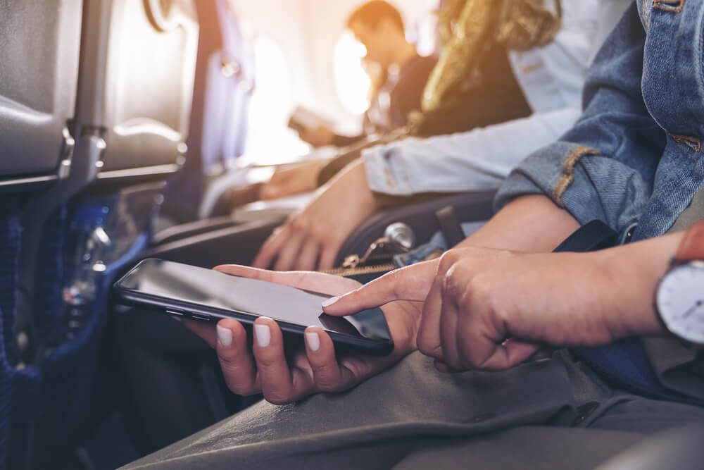 Passenger using a smartphone to read Afuzion news on an airplane. | Afuzion