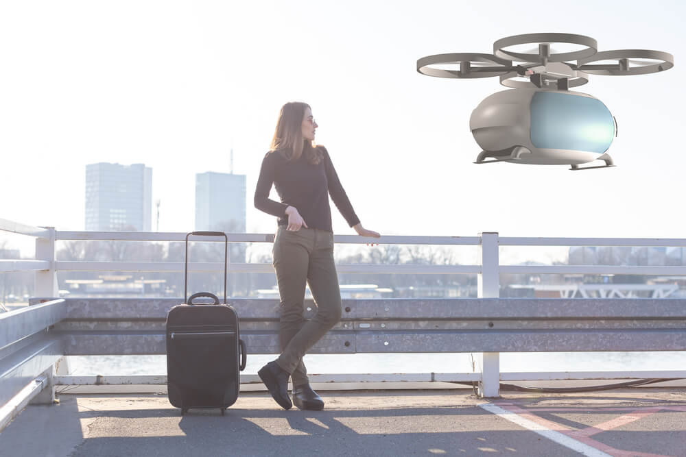 Woman standing beside a suitcase on a bridge, watching a news-covered passenger drone by Afuzion flying nearby. | Afuzion